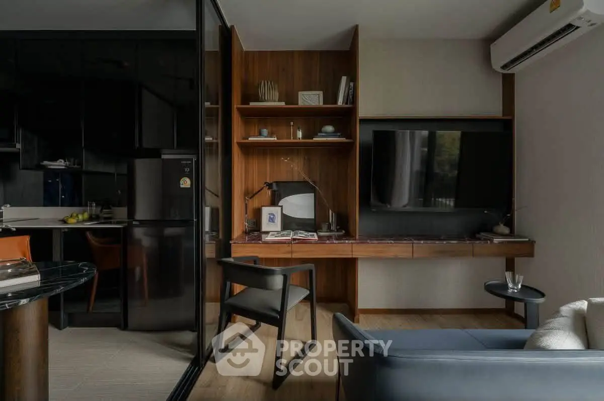 Modern living room with sleek furniture and integrated workspace, featuring a wall-mounted TV and air conditioning.