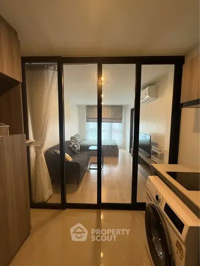 Modern apartment with glass partition, cozy living room, and washing machine.
