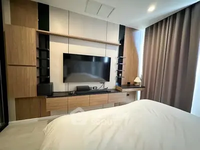Modern bedroom with sleek wooden entertainment unit and large TV, featuring elegant curtains and cozy bedding.