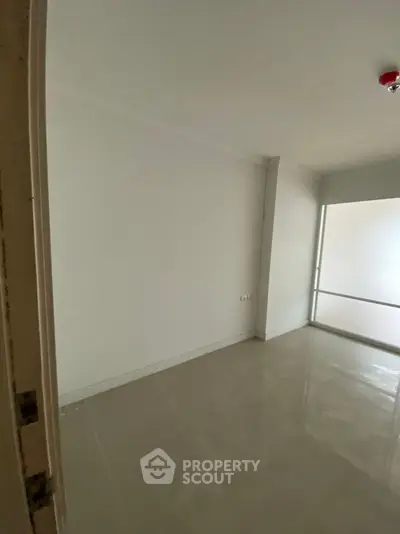 Spacious empty room with glossy tiled floor and white walls, ideal for customization.