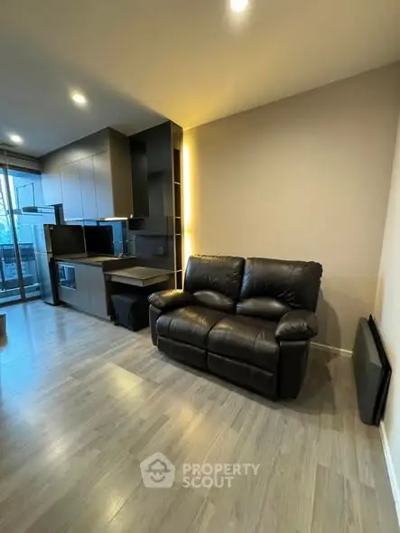 Modern living room with sleek kitchen and cozy leather sofa in open layout apartment.