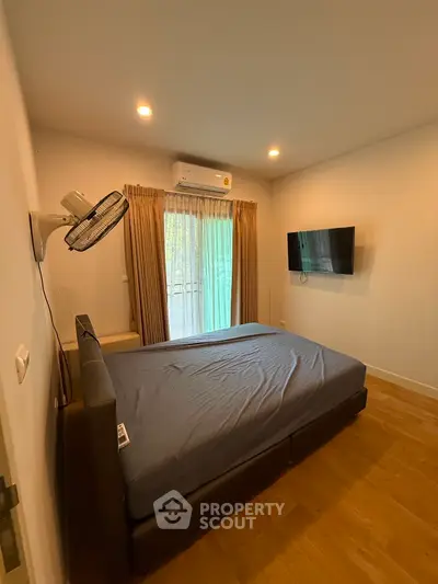 Cozy bedroom with modern decor, featuring a wall-mounted TV and air conditioning, perfect for relaxation.