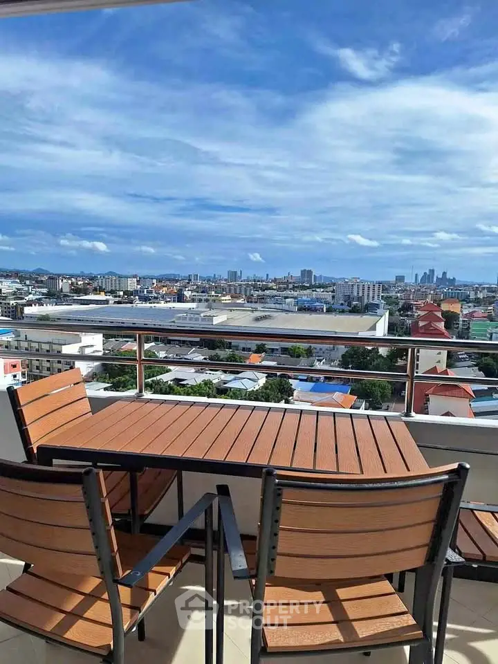 Stunning cityscape view from a modern balcony with outdoor seating, perfect for relaxation.