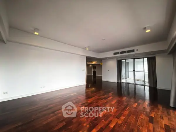 Spacious living room with hardwood floors and large windows for natural light.