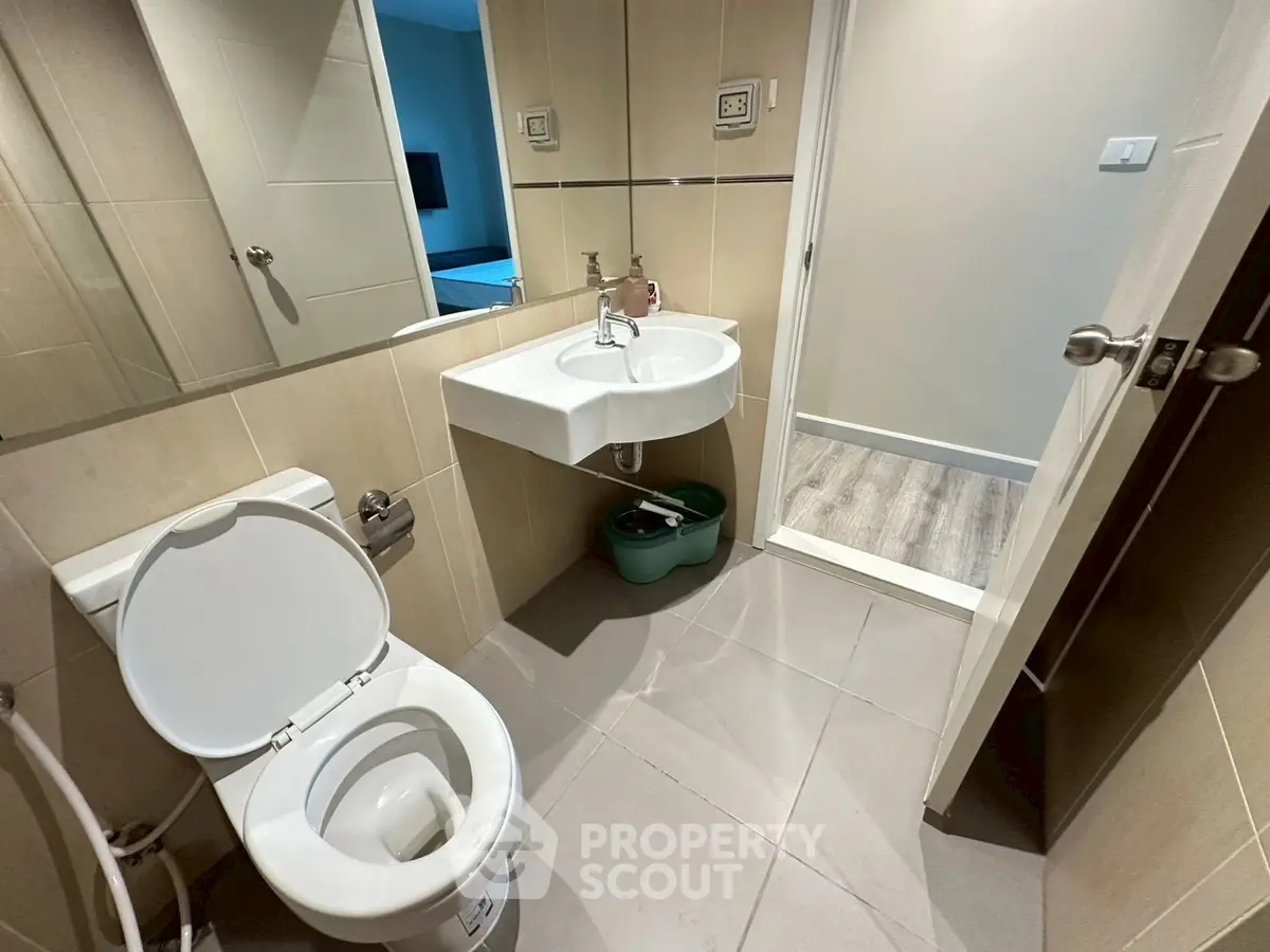Modern bathroom with sleek fixtures and neutral tiles, featuring a stylish sink and toilet.