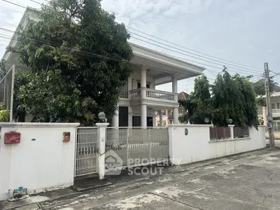 Spacious two-story house with gated entrance and lush greenery