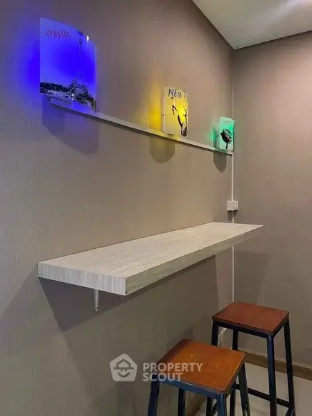 Modern minimalist interior with wall-mounted table and stools, featuring artistic city-themed lighting.