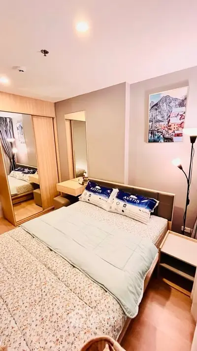 Cozy bedroom with modern decor and ample natural light, featuring a stylish bed and mirrored wardrobe.