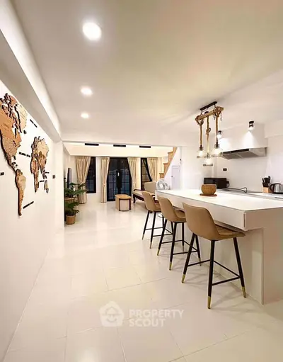Modern open-plan kitchen and living area with stylish decor and ample lighting.