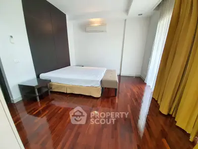Spacious bedroom with polished wooden floors and modern furnishings in a luxurious apartment.