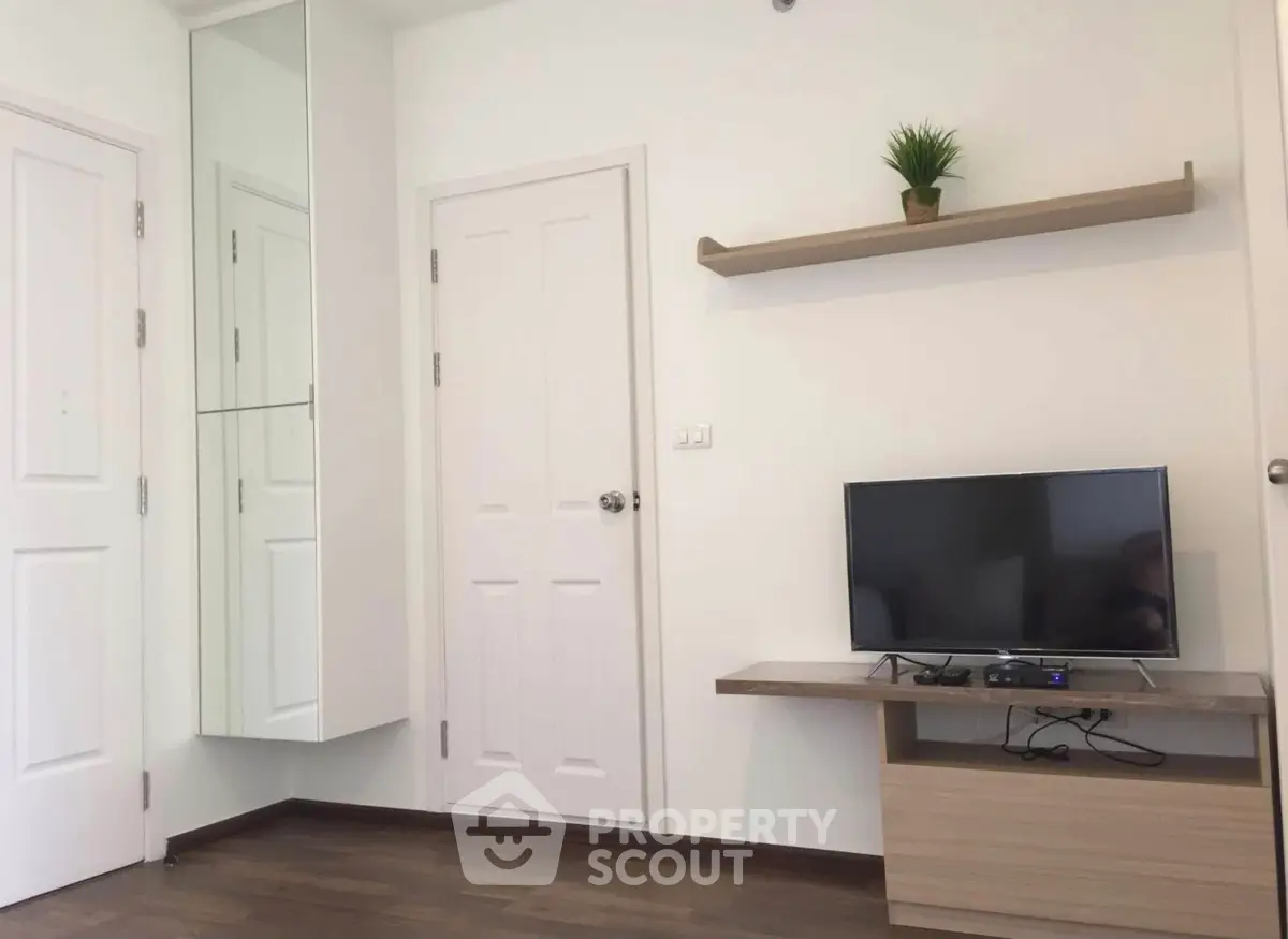 Modern living room with TV, wooden flooring, and minimalist decor