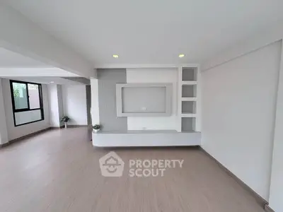 Spacious modern living room with sleek built-in shelving and large windows for natural light.