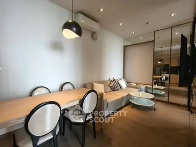 Modern living room with stylish dining area and cozy seating, featuring elegant lighting and mirrored wall.