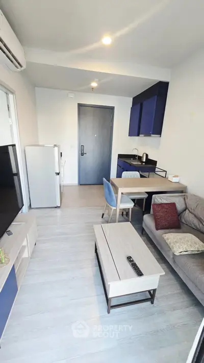 Modern living room with open kitchen, stylish furniture, and sleek design in a cozy apartment.