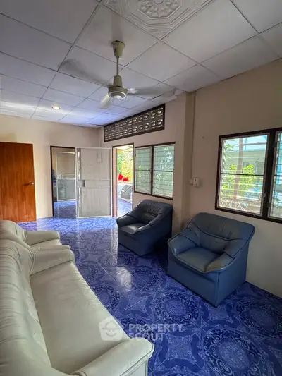 Spacious living room with blue patterned floor and comfortable seating, perfect for relaxation.