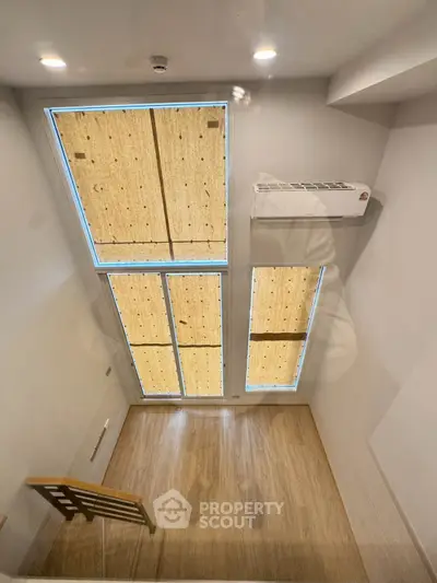 Modern loft interior with large windows and wooden flooring, featuring a sleek air conditioning unit.