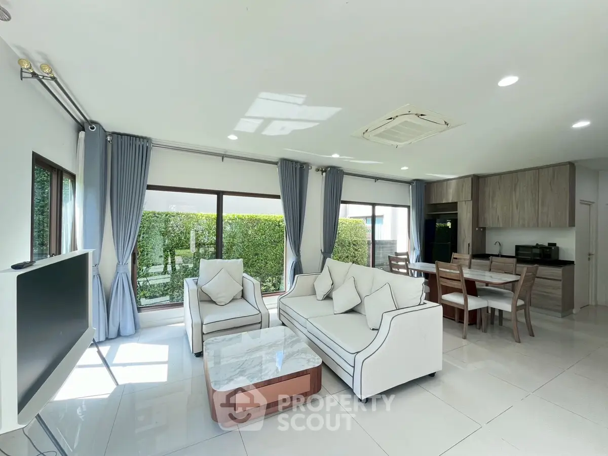 Spacious modern living room with elegant furniture and large windows offering garden views.
