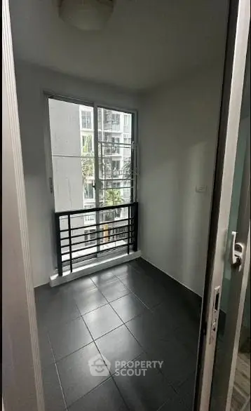 Compact room with large window and modern black railing, ideal for urban living.