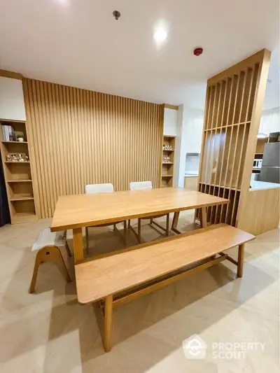 Modern dining area with wooden table and benches, featuring minimalist design and warm tones.