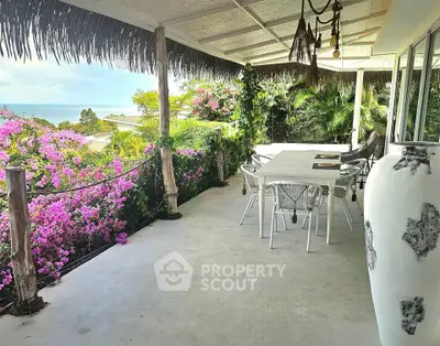 Stunning balcony with ocean view and lush greenery, perfect for outdoor dining and relaxation.