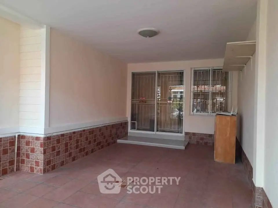 Spacious covered parking area with tiled flooring and secure entrance in a residential property.