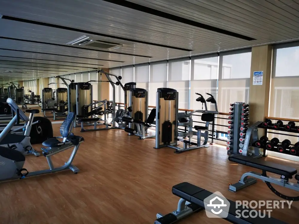 Spacious modern gym with state-of-the-art fitness equipment and large windows for natural light.