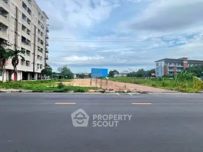 Prime real estate land for development with road access and nearby buildings.