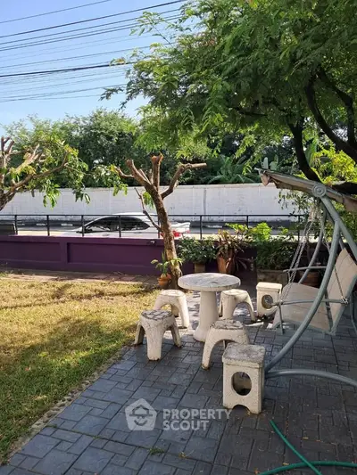 Charming garden patio with outdoor seating and lush greenery, perfect for relaxation.
