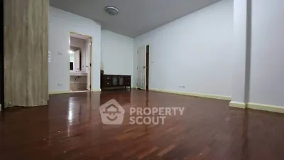 Spacious empty room with wooden flooring and neutral walls, ideal for customization.