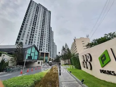 Modern high-rise residential building with landscaped entrance and branded signage.