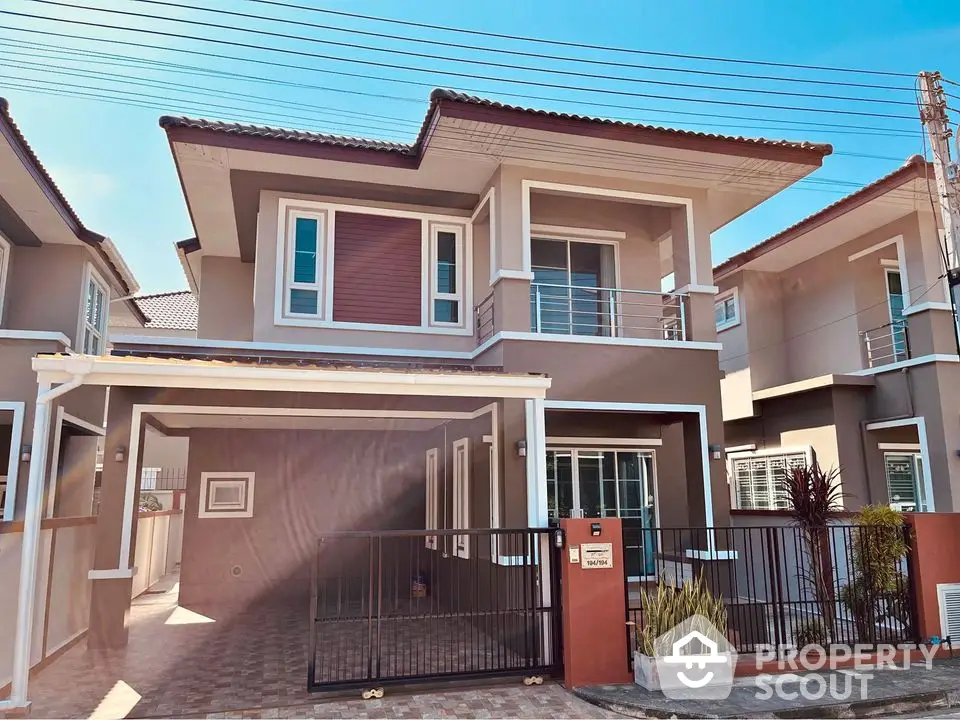 Modern two-story house with gated driveway and contemporary design in a suburban neighborhood.