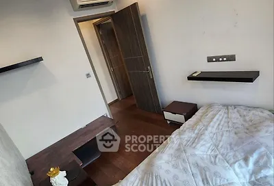 Cozy bedroom with modern decor and wooden flooring, featuring a comfortable bed and minimalist furniture.