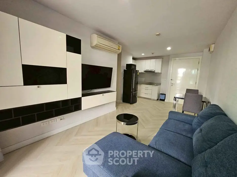 Modern living room with sleek furniture and open kitchen layout in a stylish apartment.