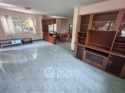 Spacious living room with wooden cabinets and dining area, featuring large windows for natural light.