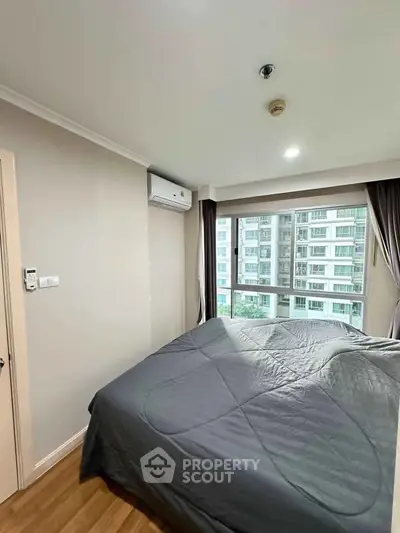 Modern bedroom with large window offering city view in high-rise apartment