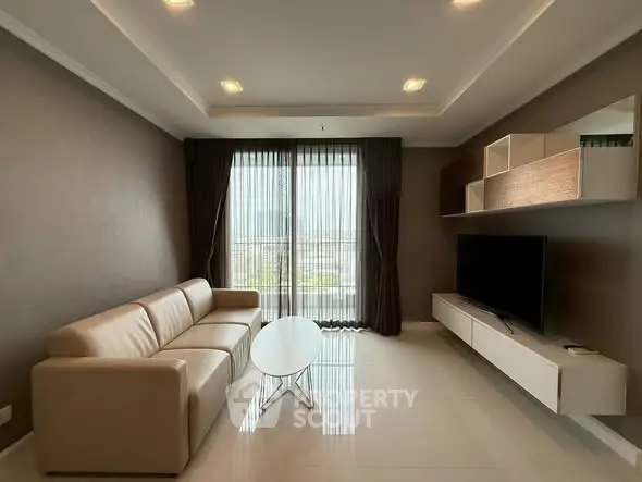 Modern living room with sleek furniture and large window offering natural light.