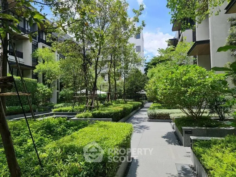 Lush garden pathway in modern residential complex with vibrant greenery.