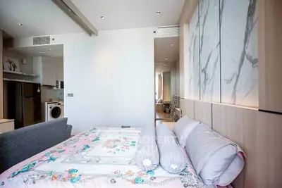 Modern bedroom with stylish decor and open layout featuring a washing machine and fridge.