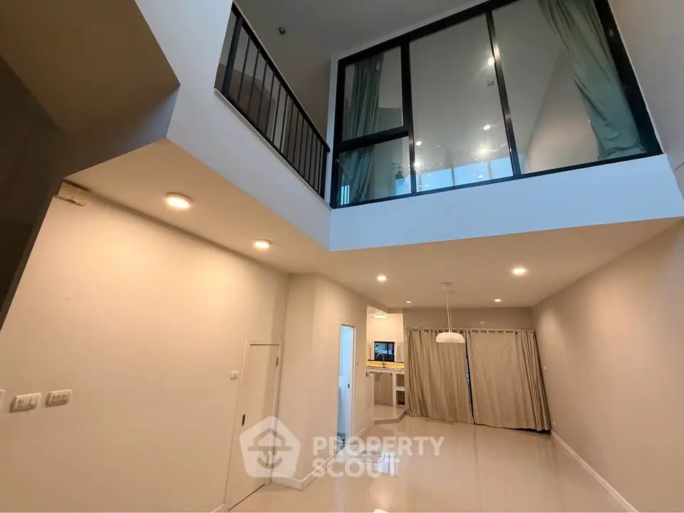 Spacious modern living room with high ceiling and large windows in a contemporary apartment.