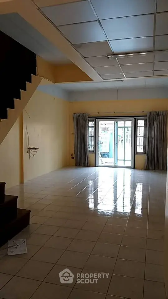 Spacious empty living room with tiled floor and large windows for natural light.
