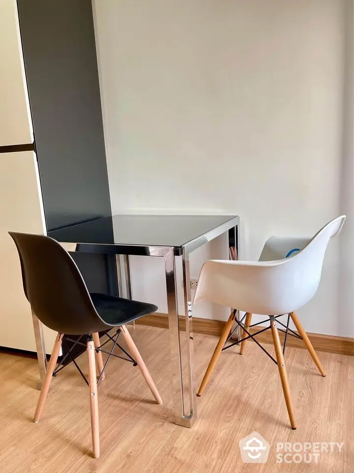 Modern dining area with sleek table and stylish chairs on wooden flooring.