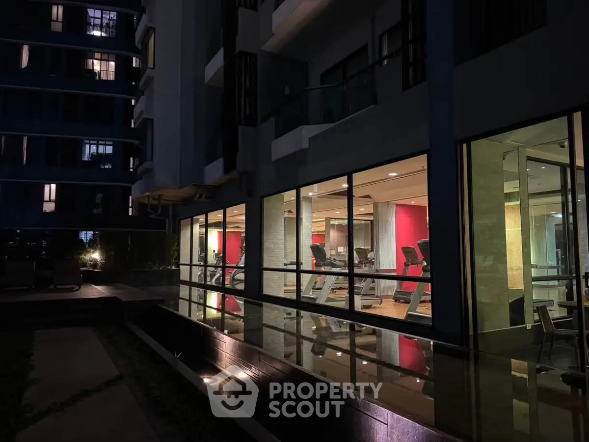 Modern gym with large windows in a residential building, showcasing fitness equipment and sleek design.