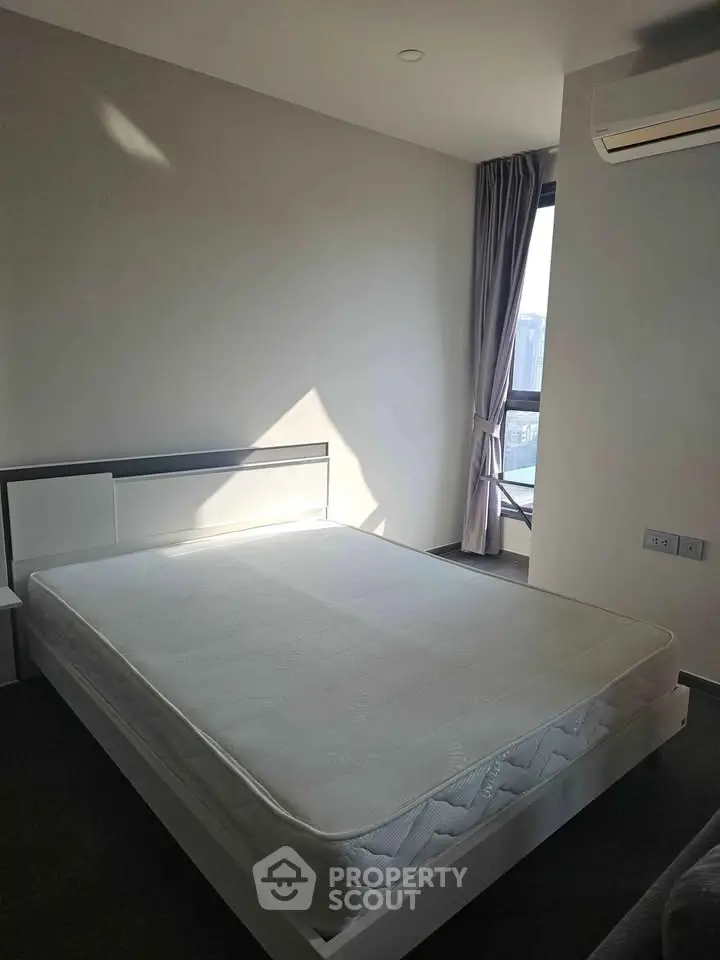 Modern bedroom with large window and minimalist design, featuring a comfortable bed and air conditioning.