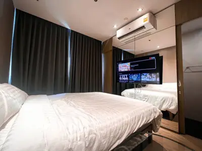 Modern bedroom with mirrored wall and mounted TV, featuring sleek air conditioning unit.