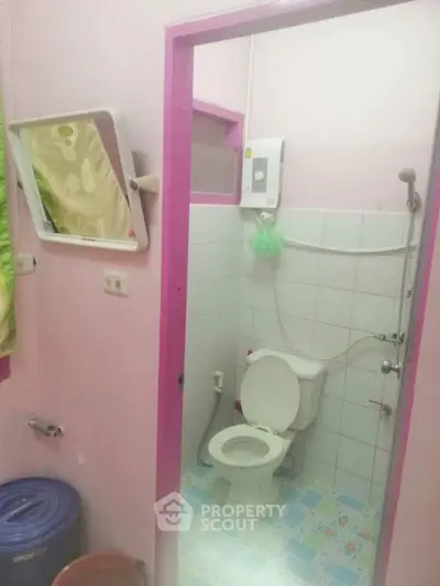 Cozy bathroom with pink accents and essential fixtures, perfect for compact spaces.