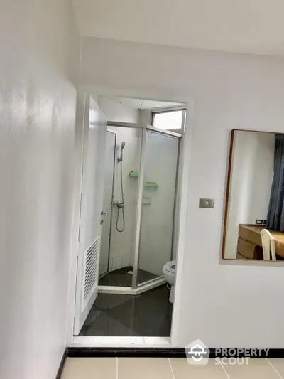 Compact bathroom with glass shower enclosure and modern fixtures in a cozy apartment.