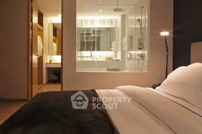 Luxurious bedroom with ensuite bathroom featuring modern glass shower and elegant decor.