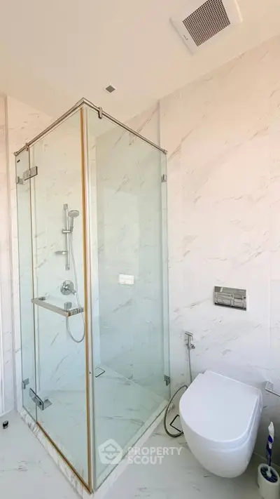 Modern bathroom with glass shower enclosure and wall-mounted toilet in a bright, minimalist design.
