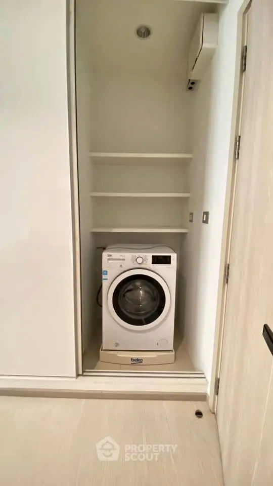 Compact laundry space with modern washing machine in sleek storage area.