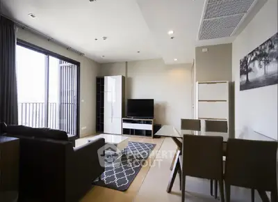 Modern living room with sleek furniture and large windows opening to a balcony.